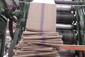 A photo depicting the manufacturing process of jute bags, showcasing machinery and workers involved in the production